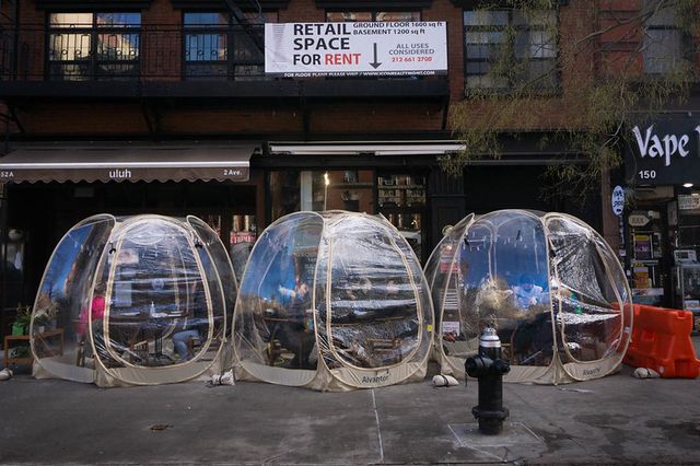 Plastic bubbles for outdoor dining line the sidewalk outside a NYC restaurant.